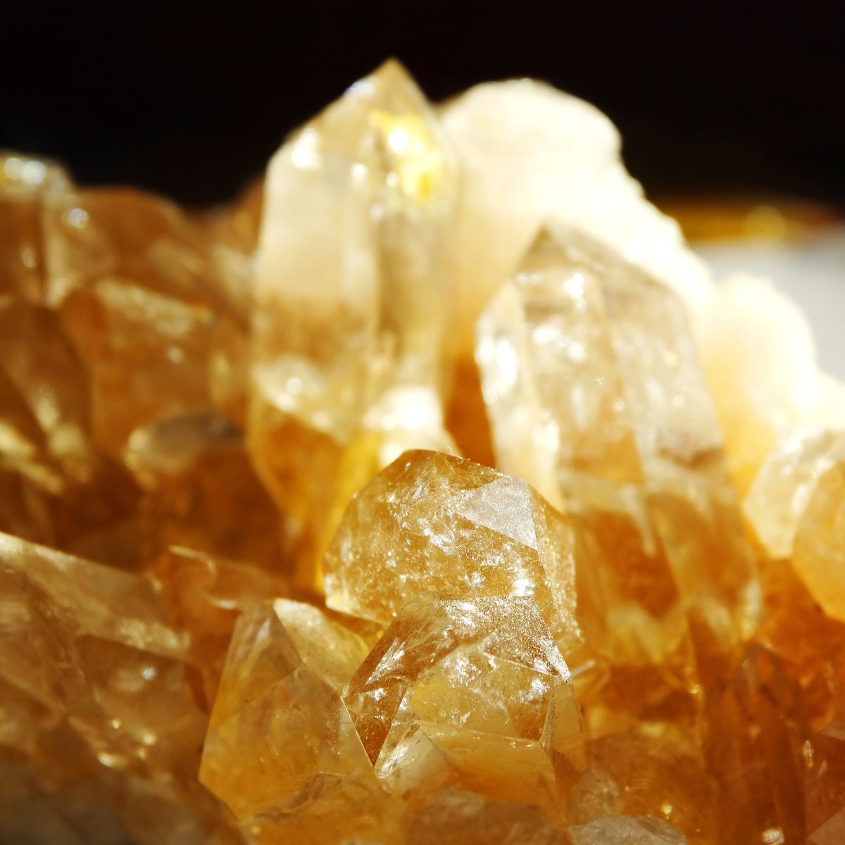 Close-up of a cluster of yellow and clear translucent crystals with sharp edges, reflecting light, reminiscent of exquisite November birthstone jewelry.